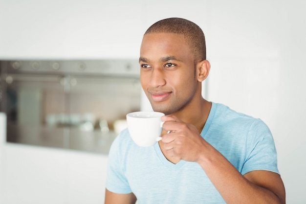 Uomo bello che tiene tazza in cucina