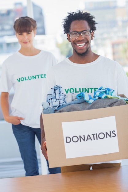 Handsome man holding donation box next to a colleague