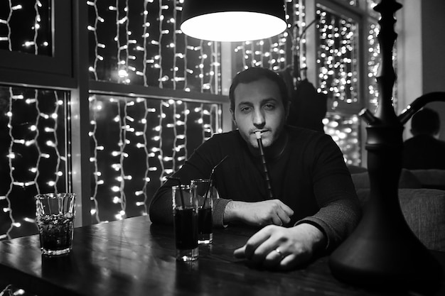 Handsome man holding glass of alcohol with ice in a night club