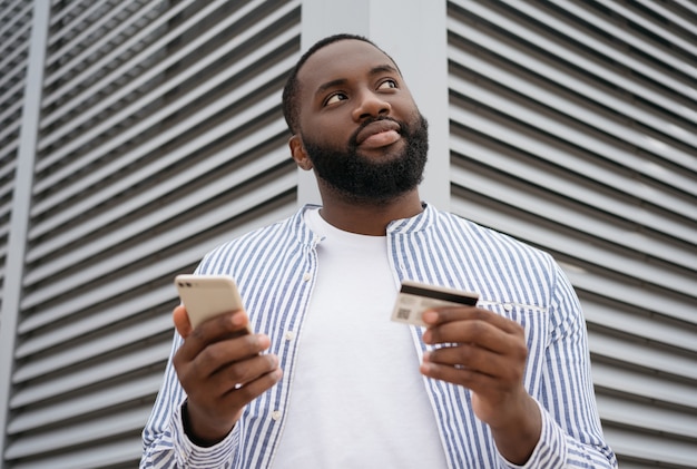 Красивый мужчина держит мобильный телефон и делает покупки в Интернете