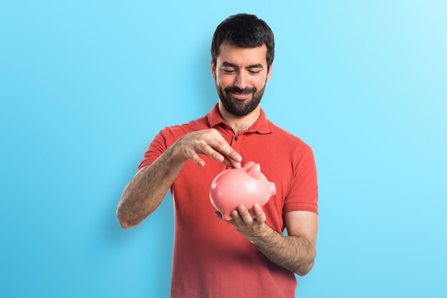 Handsome man holding a piggybank on colorful background