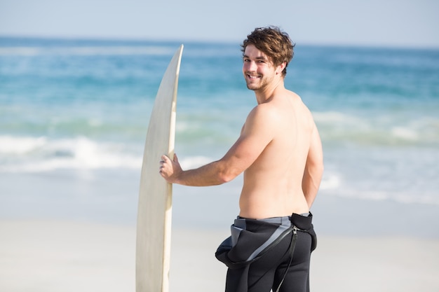 Handsome man holding surfboard on the beach