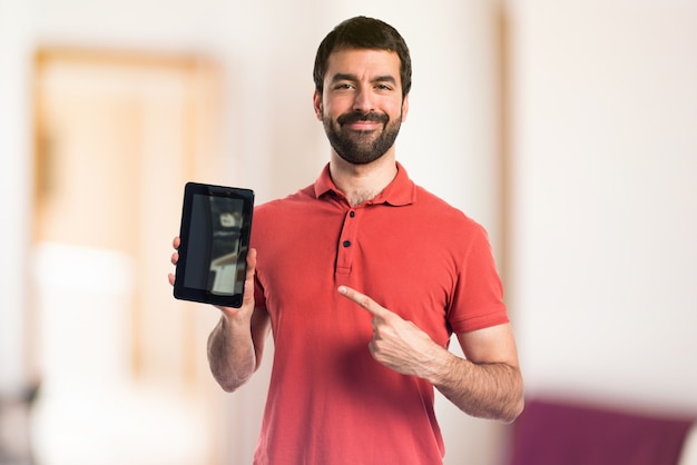 Handsome man holding a tablet on unfocused background