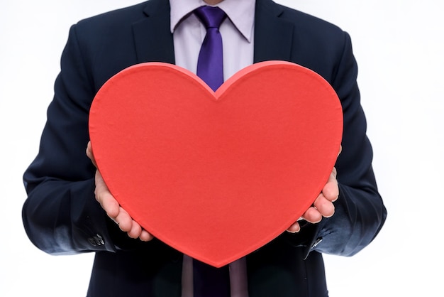 Handsome man holds toy heart on white background