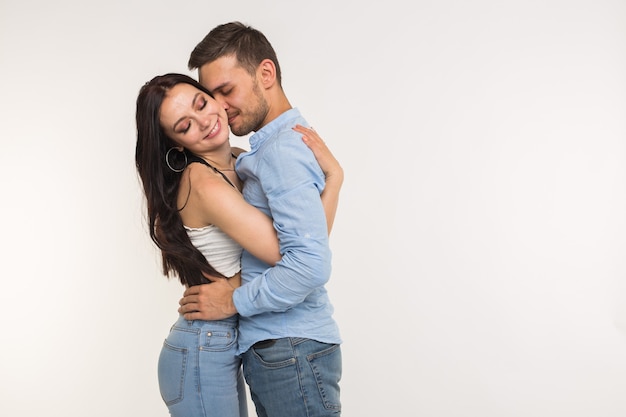 Photo handsome man hugging his girlfriend on white surface with copy space