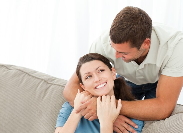 Handsome man hugging his wife while resting on the sofa 