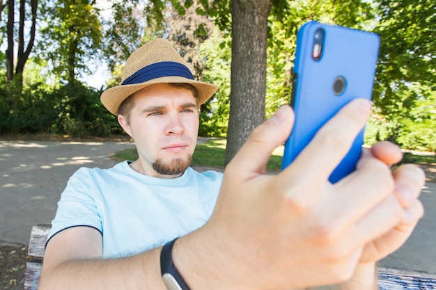 Handsome man is taking a selfie outdoor - caucasian people - nature, people, lifestyle and technology concept.