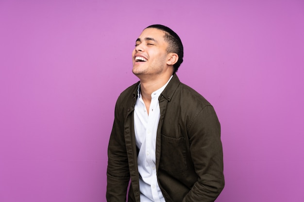 Handsome man isolated on blue wall laughing