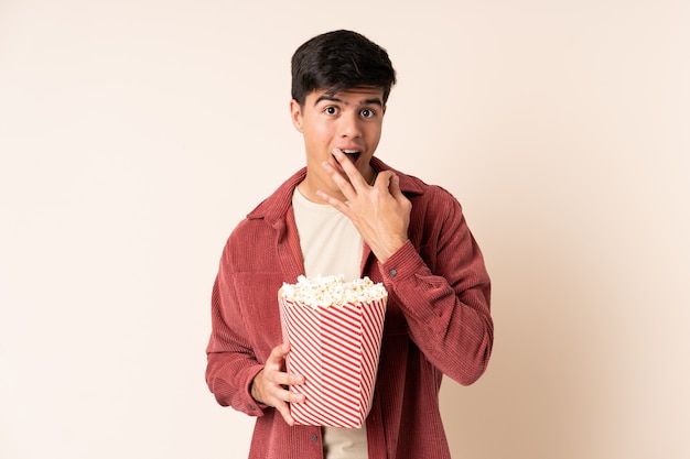 Handsome man over isolated holding a big bucket of popcorns