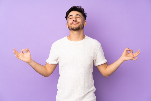 handsome man over isolated wall in zen pose