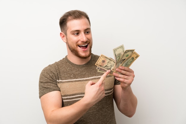 Photo handsome man over isolated white wall taking a lot of money