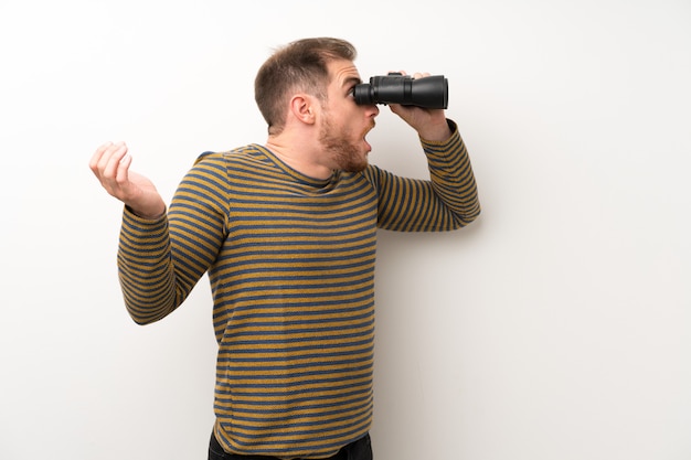 Photo handsome man over isolated white wall with black binoculars