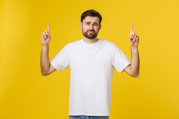 Handsome man over isolated yellow wall frustrated and pointing to the front.