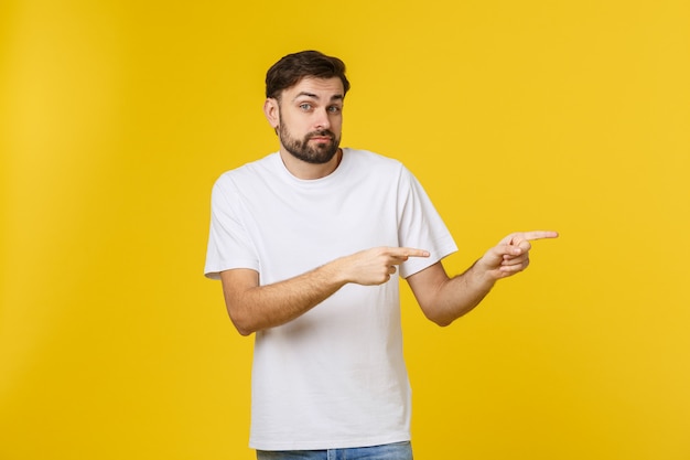 Handsome man over isolated yellow wall frustrated and pointing to the front.