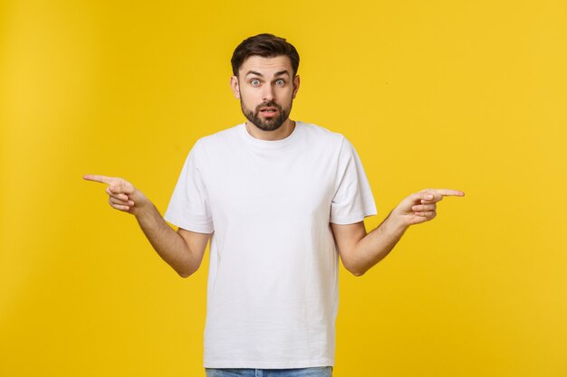 Handsome man over isolated yellow wall frustrated and pointing to the front.