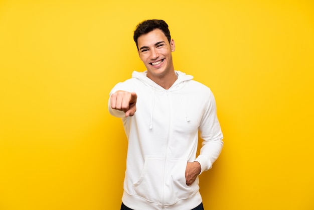 Handsome man over isolated yellow wall pointing to the front