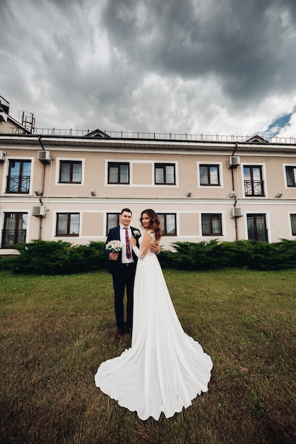 Handsome man kisses his beautiful wife and holds her bridal bouquiet