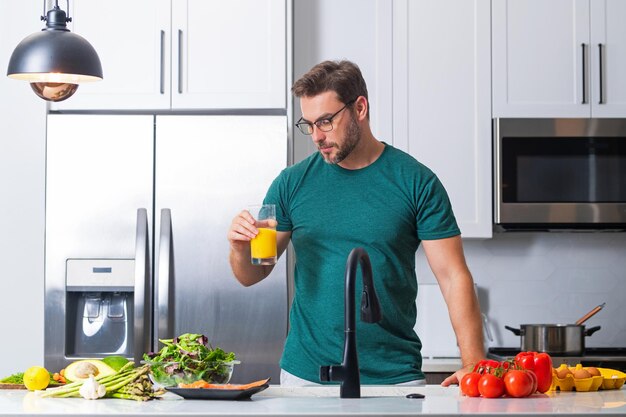 Handsome man in the kitchen is preparing healthy fruits salad and meat man preparing food at kitchen