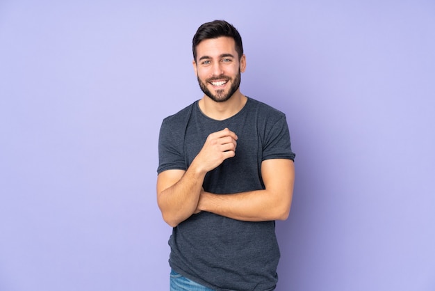 handsome man laughing over isolated purple background