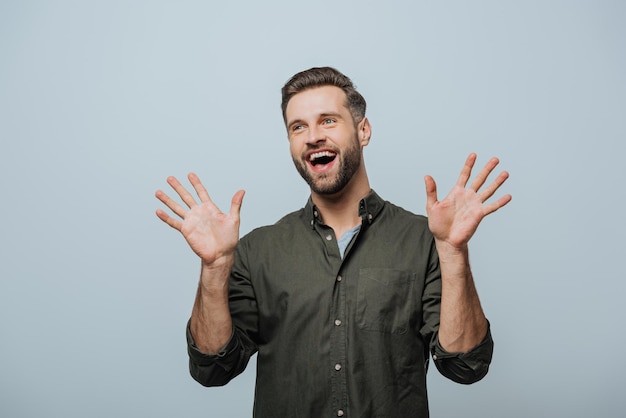 Handsome man laughing and looking away isolated on grey