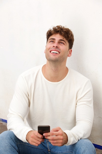 Handsome man laughing and sitting with mobile phone