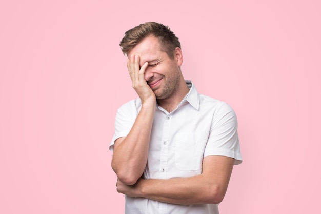 Handsome man laughing while covering his face with a hand