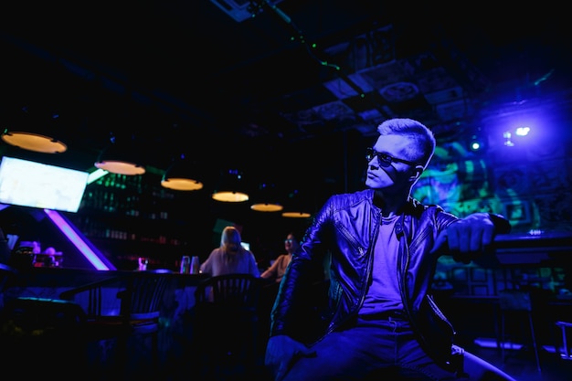 Handsome man in leather jacket with sunglasses and neon lights