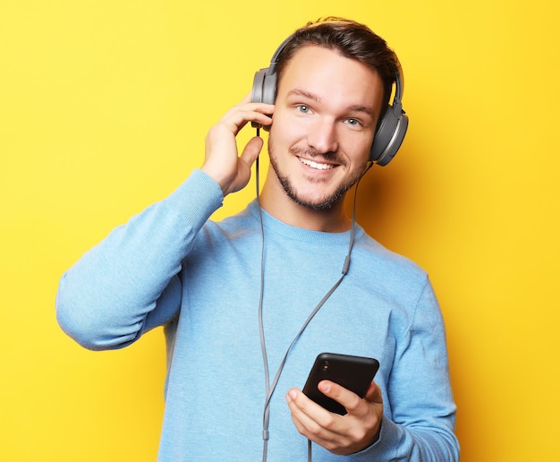 Handsome Man lictening to music over yellow background