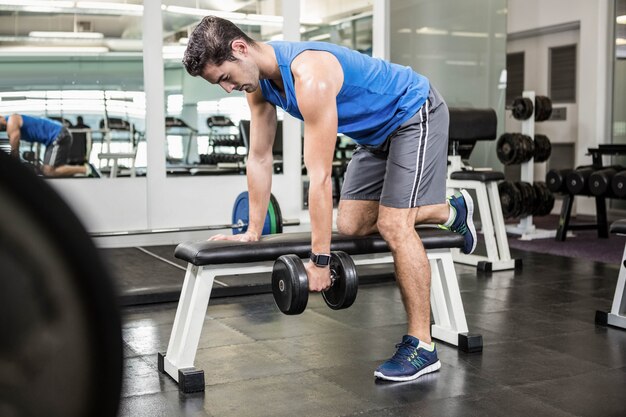 Handsome man lifting dumbbells on bench 