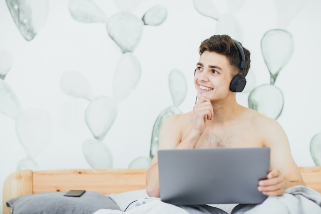 Handsome man listening to music in the morning and working on his laptop