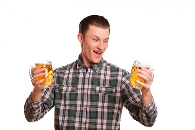 Handsome man looking excited holding two glasses of beer isolated on white. Attractive happy man smiling joyfully, posing with drinks