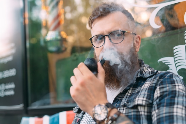 Foto bell'uomo o boscaiolo, barbuto hipster, con barba e baffi pipa da fumo.
