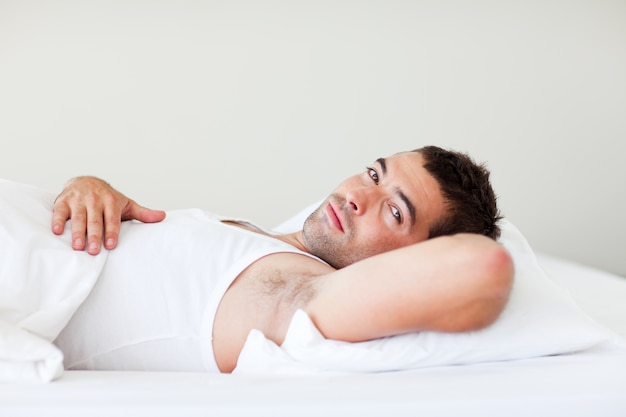 Photo handsome man lying in bed