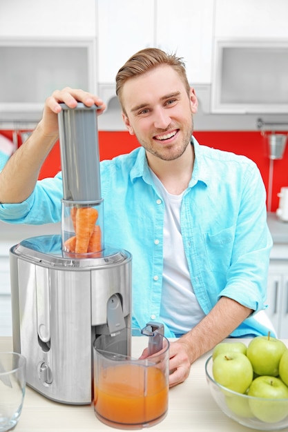 Handsome man making juice in kitchen