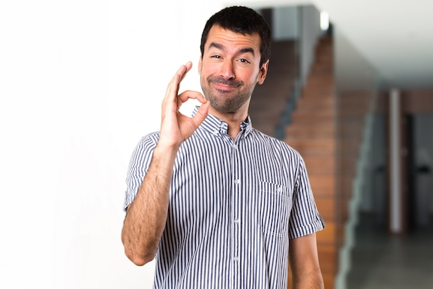 Handsome man making OK sign inside house