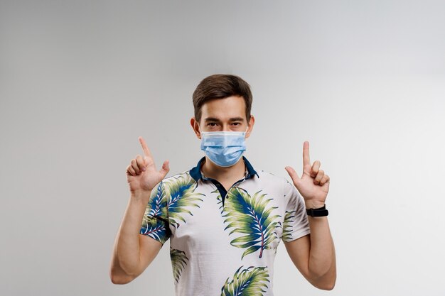 Handsome man in medical mask points up