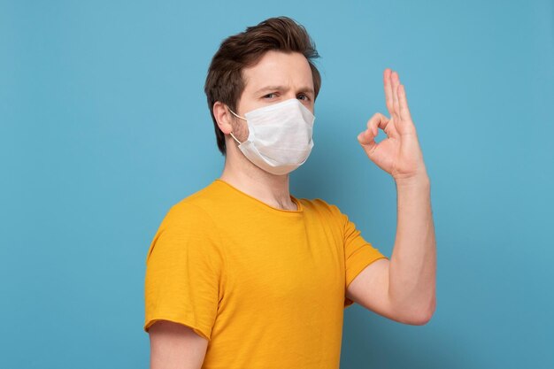 Handsome man in medical mask showing okay gesture