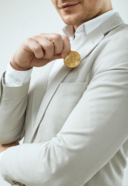 Handsome man model in a fashion gray suit holds a Bitcoin