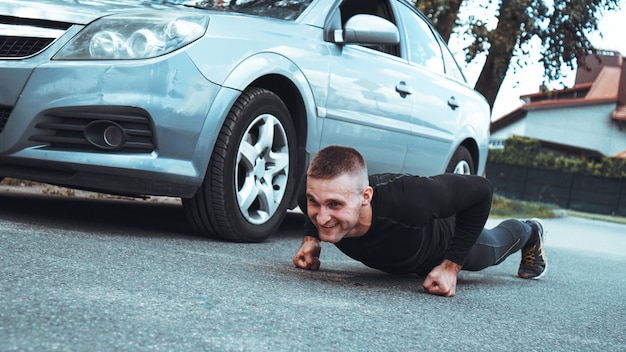 車の近くのハンサムな男。アスリートはマシンの横でしぼりました。車VS男