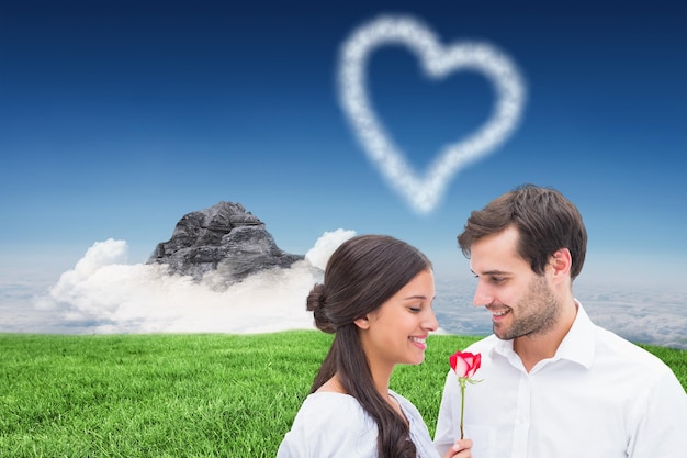 山の頂上の雲に対して彼のガール フレンドにバラを提供するハンサムな男