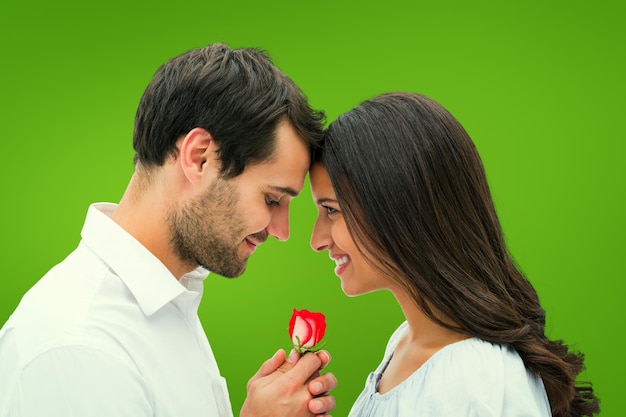 Handsome man offering his girlfriend a rose against green vignette