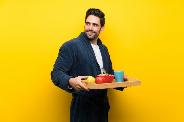 Handsome man in pajamas isolated on yellow wall