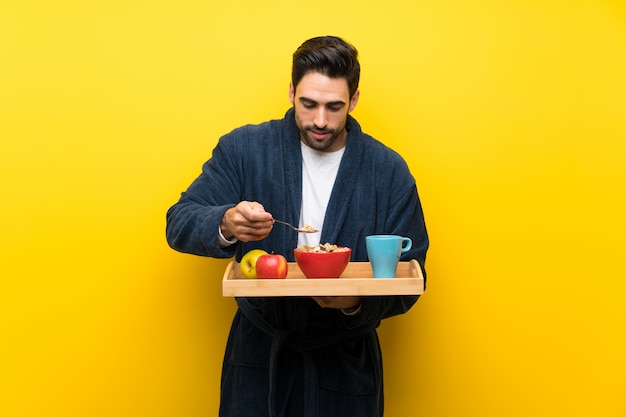 Handsome man in pajamas over isolated yellow wall