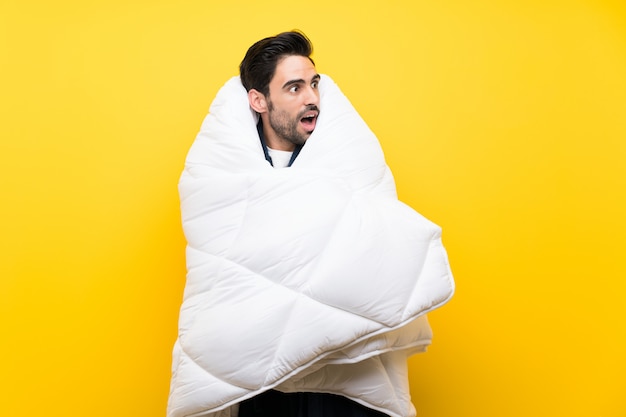 Handsome man in pajamas over isolated yellow wall