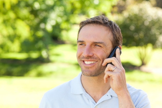 Bell'uomo telefonando nel parco