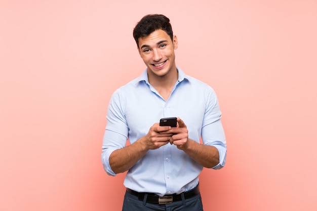 Handsome man over pink sending a message with the mobile