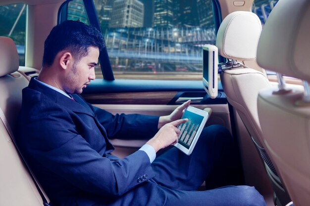 Handsome man pointing his tablet in the car