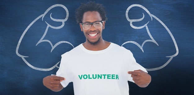 Handsome man pointing to his volunteer tshirt against blue chalkboard