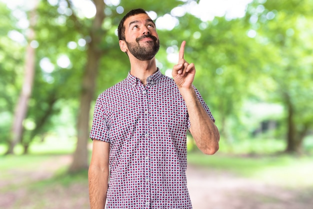 Handsome man pointing up on unfocused background