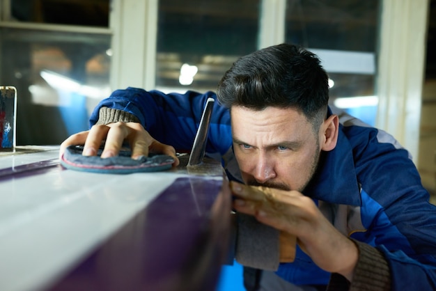 Handsome Man Polishing Surfing Board in Workshop